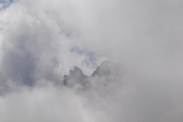 Naklejka premium Clouds almost comletly covering the sharp mountain peaks of the Chaukhi massif in the Greater Caucasus Mountain Range in Georgia, Kazbegi Region. Hiking. Georgian Dolomites. Cloudscape