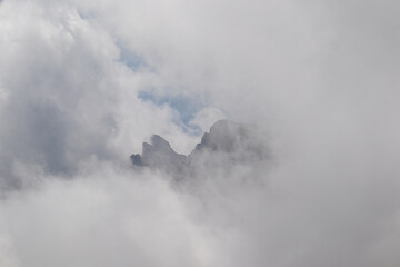 Clouds almost comletly covering the sharp mountain peaks of the Chaukhi massif in the Greater Caucasus Mountain Range in Georgia, Kazbegi Region. Hiking. Georgian Dolomites. Cloudscape