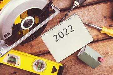 Naklejka premium 2022 Goals, DIY tools and notebook on the desk in workshop, planning home improvement projects in New Year
