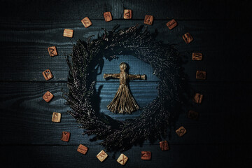 Voodoo doll, wreath and runes on grey wooden background, flat lay