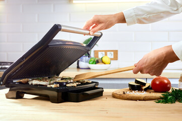 Woman holding spatula for cooking and serving barbecue on table. Grill steak on an electric stove at kitchen.