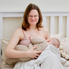 Pain and problems in a woman while breastfeeding a baby. Mother experiences discomfort while breastfeeding