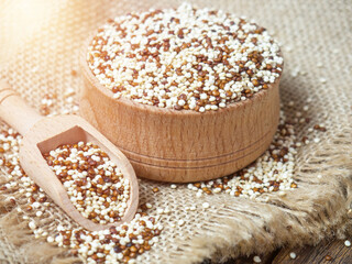 Quinoa in wooden bowl and scoop on rustic background
