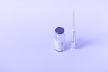Vaccine for immunization against COVID and a syringe on a colored background. Closeup medical concept