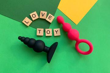 Sex toys. Two  butt plags on green background. Lettering LOVE TOY. Useful for adult, sex shop