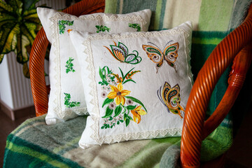 Two pillows with embroidery in the shape of flowers and butterflies.