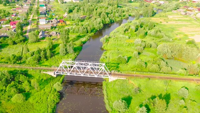 Aerial view landscape railway bridge across a small river in a rural area small town, stream in green field, top view meadow