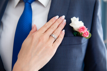 Bride's hand with wedding ring on his shoulder groom