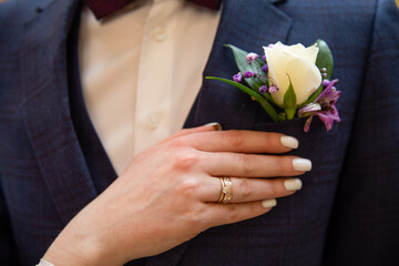 Bride's hand with wedding ring on his shoulder groom