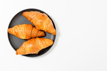 Croissants on the plate on black background. Top view.