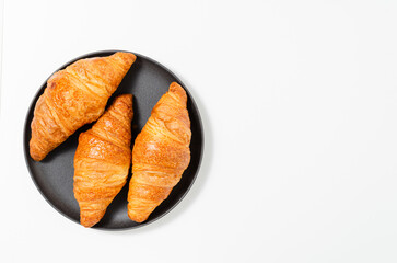Croissants on the plate on black background. Top view.