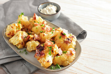 cauliflower vegetable with egg and ham on a gray plate on a wooden table, tasty recipe for a ketogenic or low carb diet, copy space, selected focus