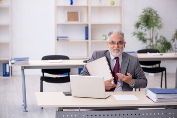 Obraz premium Old male employee working in the office