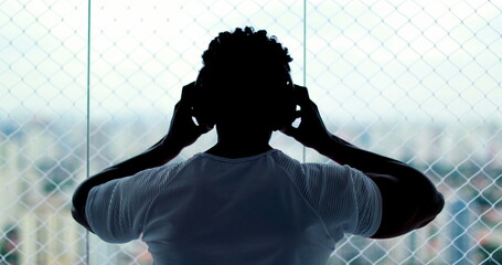 Person putting on headphones indoors listening to song, podcast, audiobook