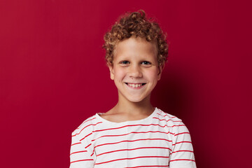 Cheerful boy in a striped T-shirt gestures with his hands red background