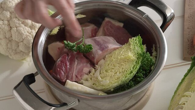 Putting marrow bones and vegetables into a pot of water - preparation of homemade beef broth or soup