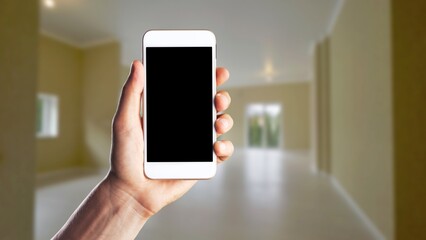 Human using smartphone, controlling smart home systems in modern apartment, blank screen
