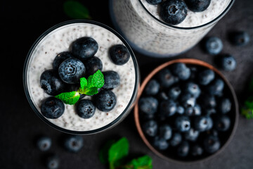 Chia pudding with blueberries on a dark background. Chia pudding, mint and blueberries on a black background.