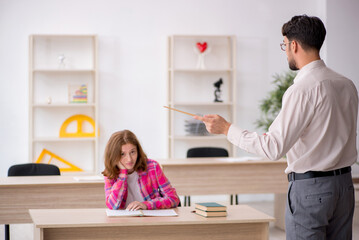 Young male teacher and redhead girl in the classroom