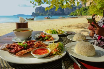 Washable wall murals Railay Beach, Krabi, Thailand Fried fish and Thai food on table on the beach at Railay beach, Krabi, Thailand, healthy eating concept