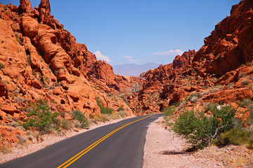 The asphalt road in the middle of the valley surrounded by red rocks