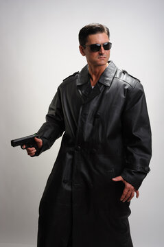 The sexy sniper poses for the photo wearing a trench coat. 