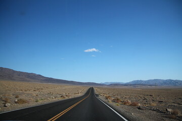 Straight road towards mountain range in horizon at Death Valley