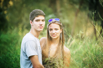 Portrait of a beautiful girl and a guy in a meadow in the summer. Children of generation z walk in nature. A couple in love celebrates Valentine's Day.