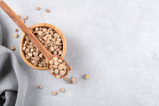 Cicerchia or indian pea in a wooden bowl and spoon on grey table background, gluten free food. Legumes known as Lathyrus Sativus, Chickling Vetch, Blue Sweet Pea made in Puglia, close up, copy space