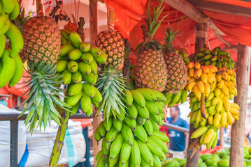 Fototapeta na wymiar Bananas and pineapples hang under the roof of street shop in Zanzibar, Tanzania.