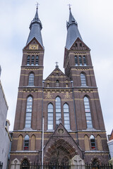 Fototapeta na wymiar Neo-Gothic Post Horn Church (Posthoornkerk, 1863) with three slender towers on bustling Haarlemmerstraat - one of most important surviving nineteenth century churches. Amsterdam, the Netherlands.