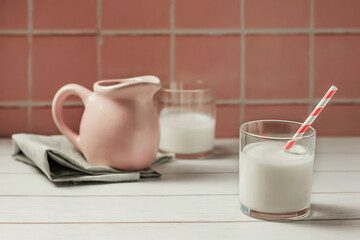 Banner of a glass of milk or yogurt and a jug of milk on a pink background. The concept of farm dairy products, dairy day. Space for copy.
