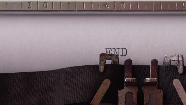 Typing phrase END OF STORY on retro typewriter. Close