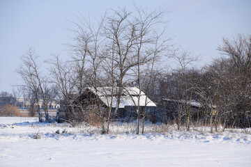 Old ruined house in the village in winter. Snow in yard.