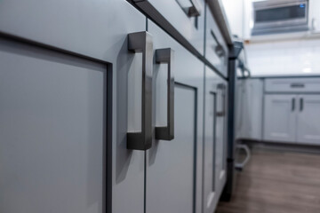 Low angle view of gray kitchen cabinet door handles inside a large, beautiful kitchen with...