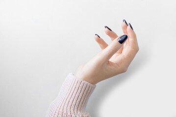 well-groomed female hand with a blue manicure and a pink sweater on a white background. isolate. place for text