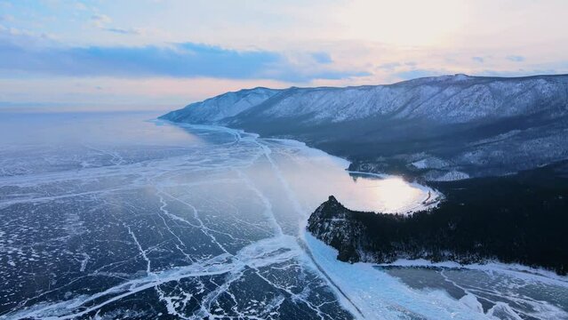 Frozen Lake Baikal, Aerial view. Beautiful winter landscape with clear smooth ice. Famous natural landmark Russia. Blue transparent ice with deep cracks, top view of a frozen lake.