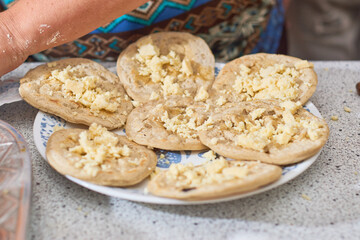 Mexican woman prepares corn sope on the plate.