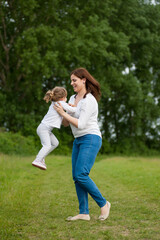 Fototapeta premium Young mother is playing with her daughter in the park