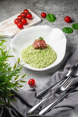 Risotto arborio rice with salmon and spinach in a plate on a gray stone table. Restaurant Menu