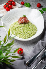 Risotto arborio rice with salmon and spinach in a plate on a gray stone table. Restaurant Menu