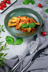 Italian pasta Conchiglioni Rigati stuffed with dry tomatoes and meat with basil and cheese on a gray stone table. Restaurant Menu