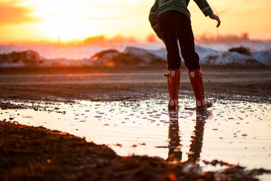 a child walking through a mud puddle during sunset - Powered by Adobe