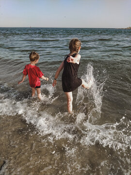 Two children playing with the waves on the seashore