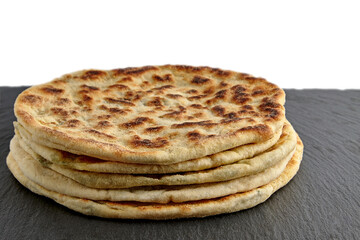 Flatbread tortilla with cheese and herbs on a dark stones plate