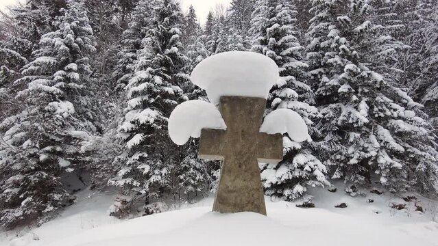 Video of a traditional old stone cross in a snowy forest on the way to the Huk waterfall and Mount Khomyak in the Carpathians, Ukraine.