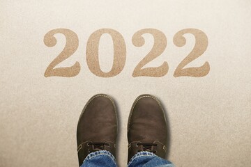 Top view of man feet standing on cement floor and 2022 text, Happy new year concept.