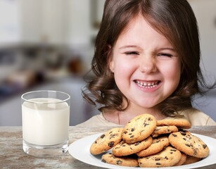 Portrait of sad girl holding glass of milk and dreaming, sitting on dinning table in kitchen...