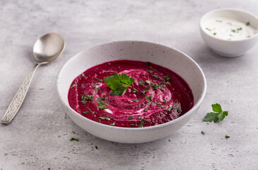 Beetroot soup puree with sour cream, herbs and spices on gray background. Delicious homemade food