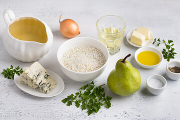 Ingredients for Vegetarian Pear and Blue Cheese Risotto: fresh pear, piece of blue cheese, rice, onion, olive oil, butter, white wine, vegetable broth, spices and herbs on a light blue background